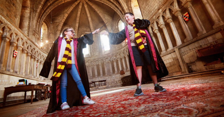 Boy and girl dressed as wizards inside Durham Cathedral - a filming location for the Harry Potter movies.